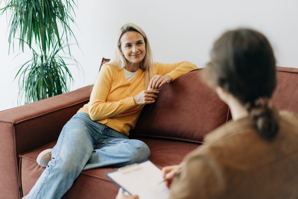 A forty-year-old woman sitting on the sofa at a consultation with a NDIS psychologist talks about her mental problems and depression.