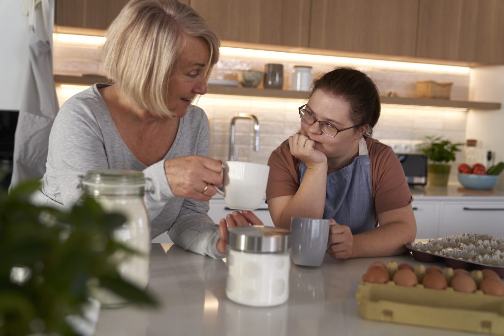 Down syndrome woman and her mother chatting over coffee during a mobile NDIS care session