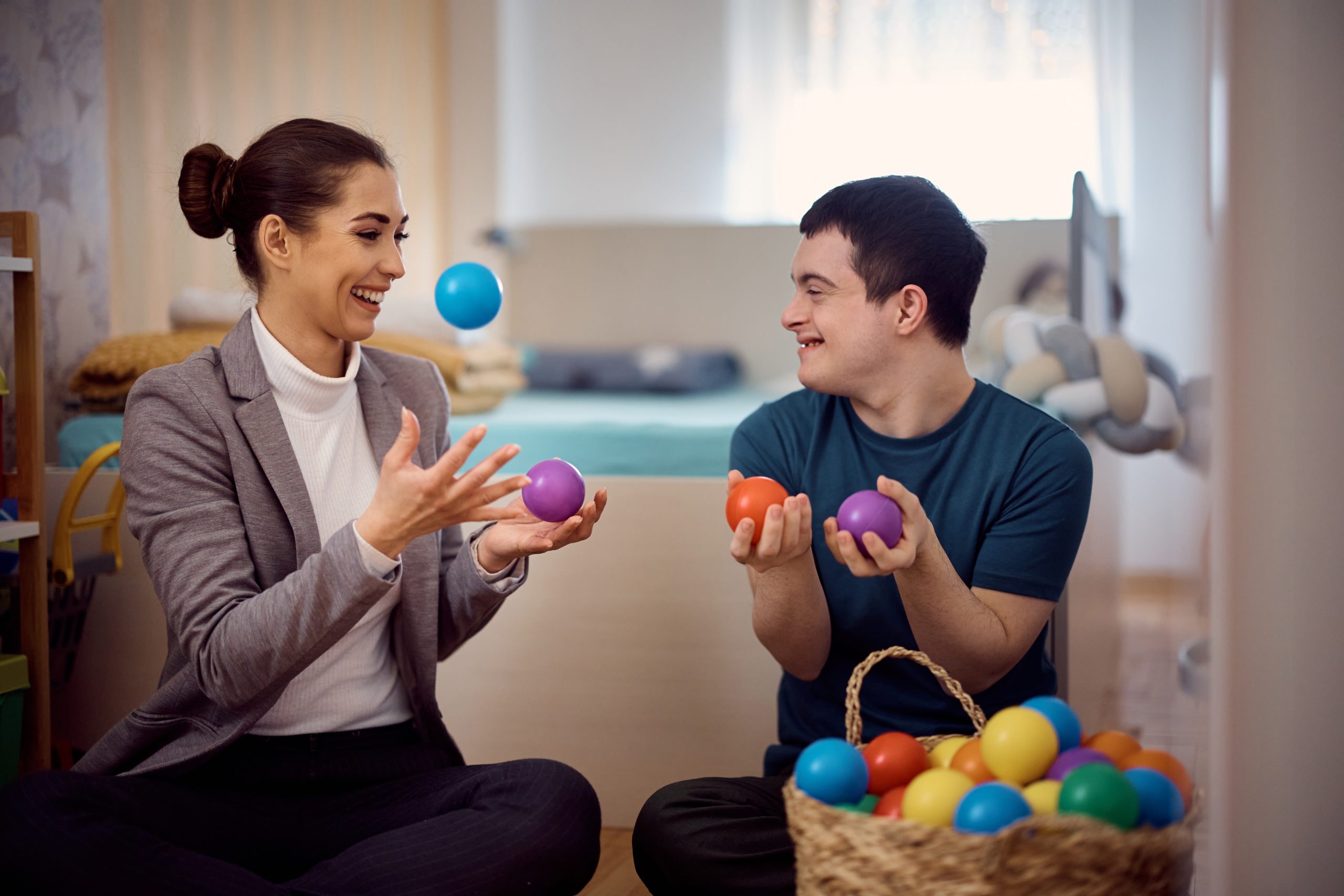 NDIS Occupational Therapy session with a woman and young boy with down syndrome juggling coloured balls